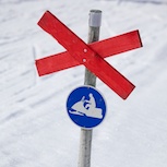 Den blå skylten betyder att det är förbjudet att köra skoter utanför leden. Det röda ledkrysset innebär att det även är en skidled. Skotern ska lämna företräde.